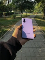 A person holding a lightweight phone case while walking in a park.