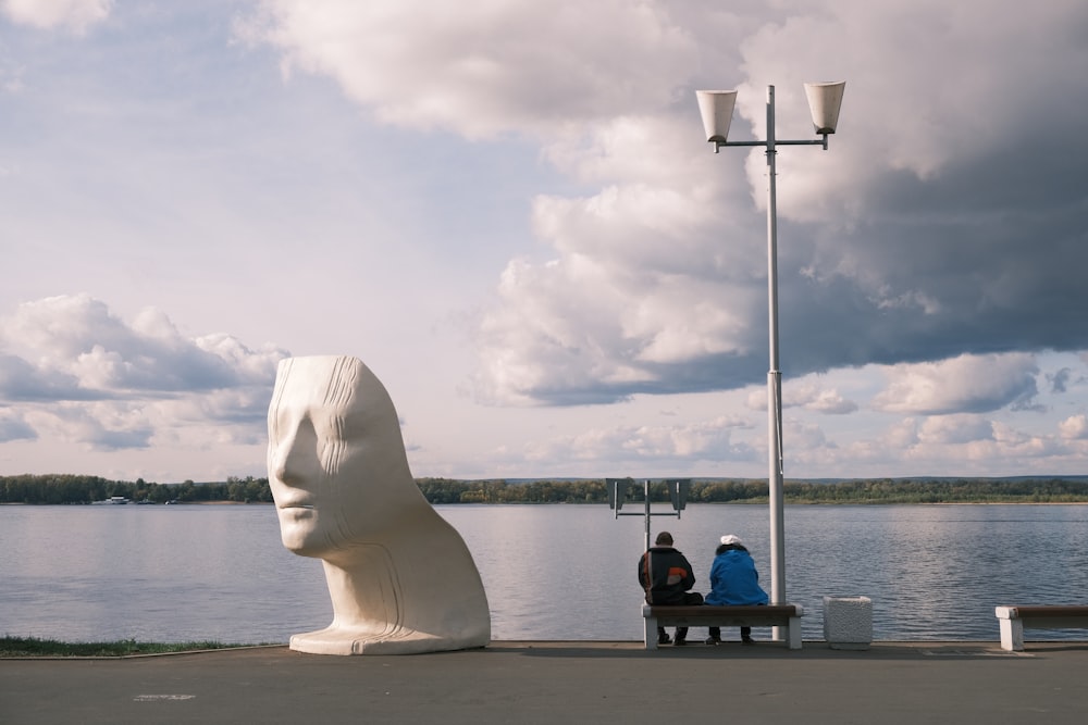 two people sitting on a bench near a body of water