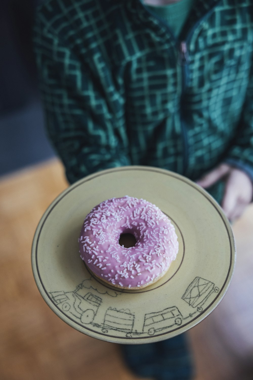 a person holding a plate with a doughnut on it