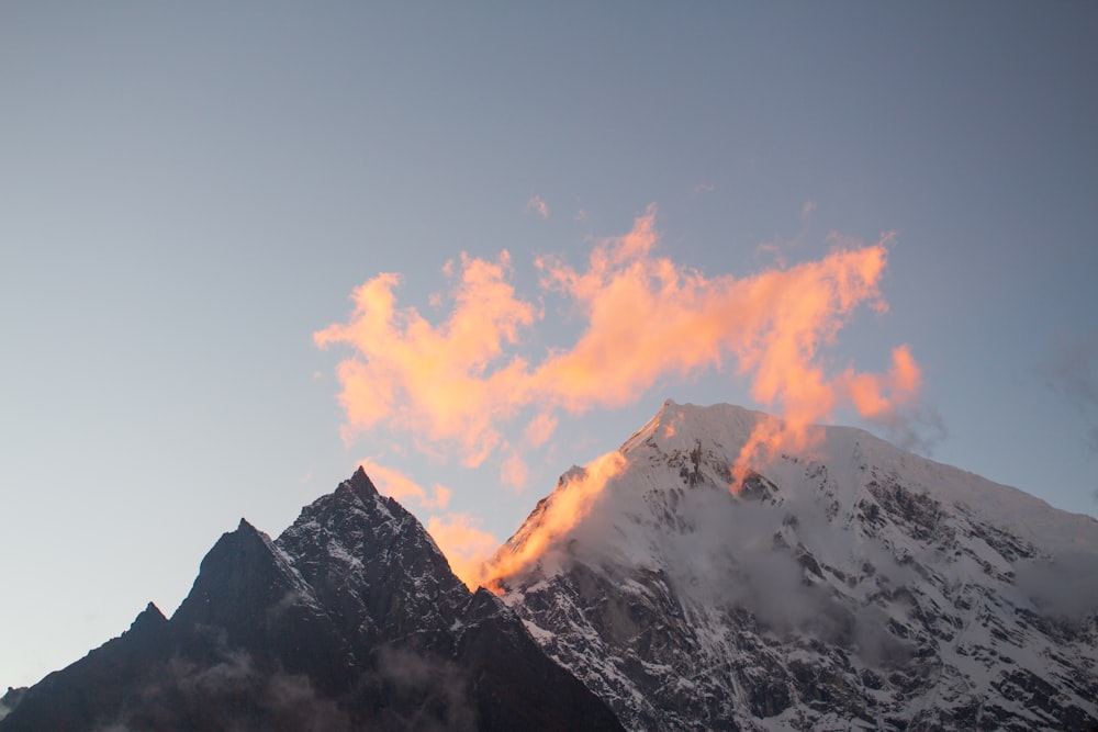 a mountain range with a pink cloud in the sky