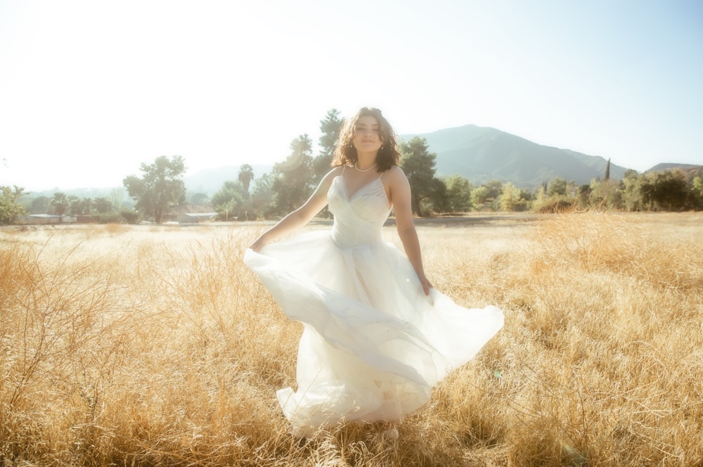 Eine Frau im weißen Kleid steht auf einem Feld