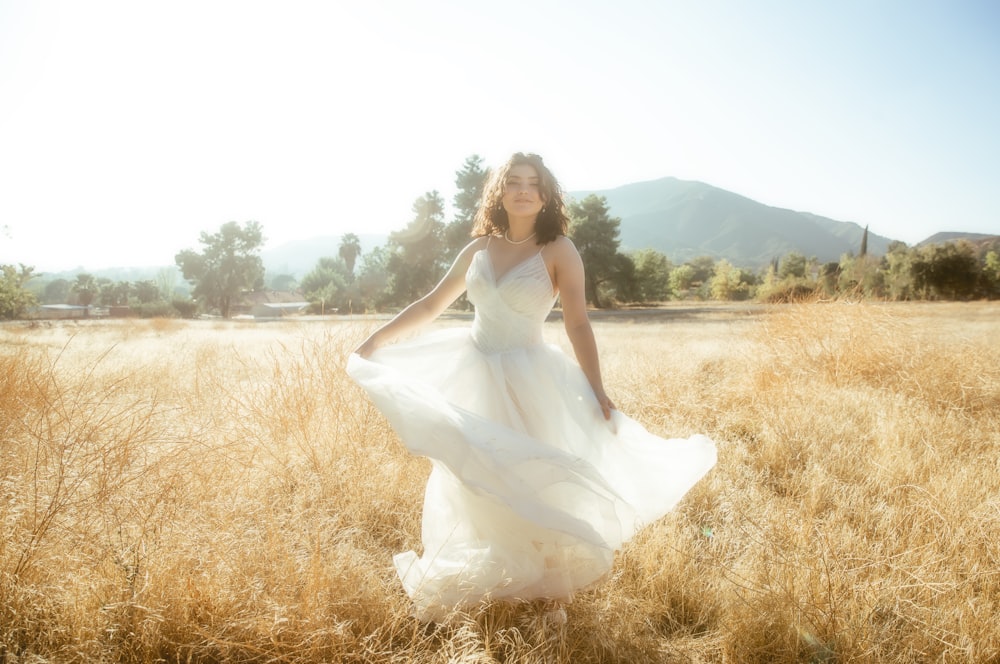 uma mulher em um vestido branco está de pé em um campo
