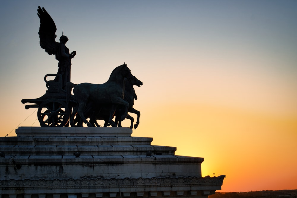 Una statua di una carrozza trainata da cavalli con un uccello in cima