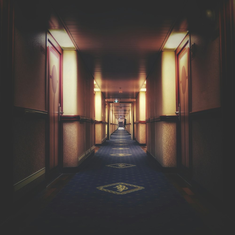 a long hallway with a blue carpet and a light at the end
