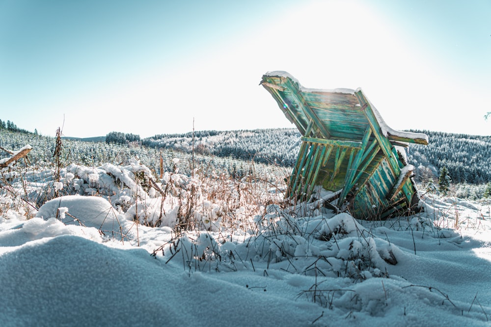 a broken chair sitting in the middle of a snow covered field