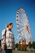 a woman standing in front of a ferris wheel