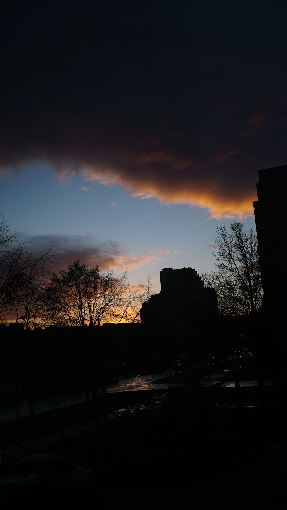 a dark sky with clouds and buildings in the background