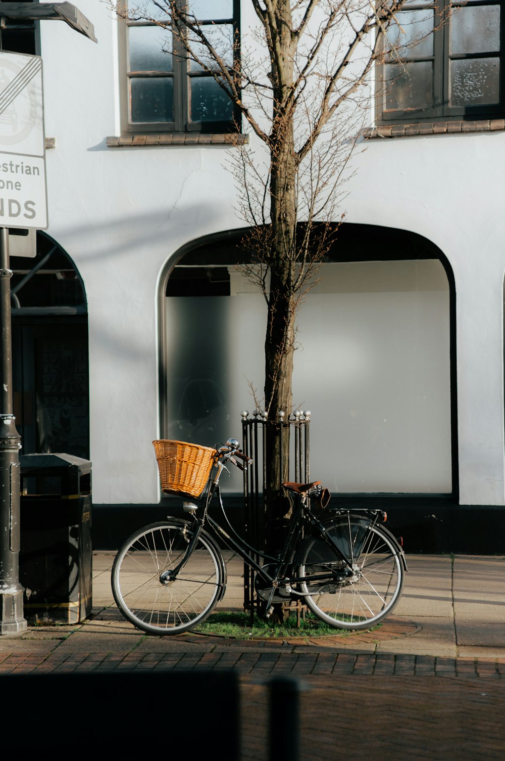 a bicycle parked next to a tree on a sidewalk