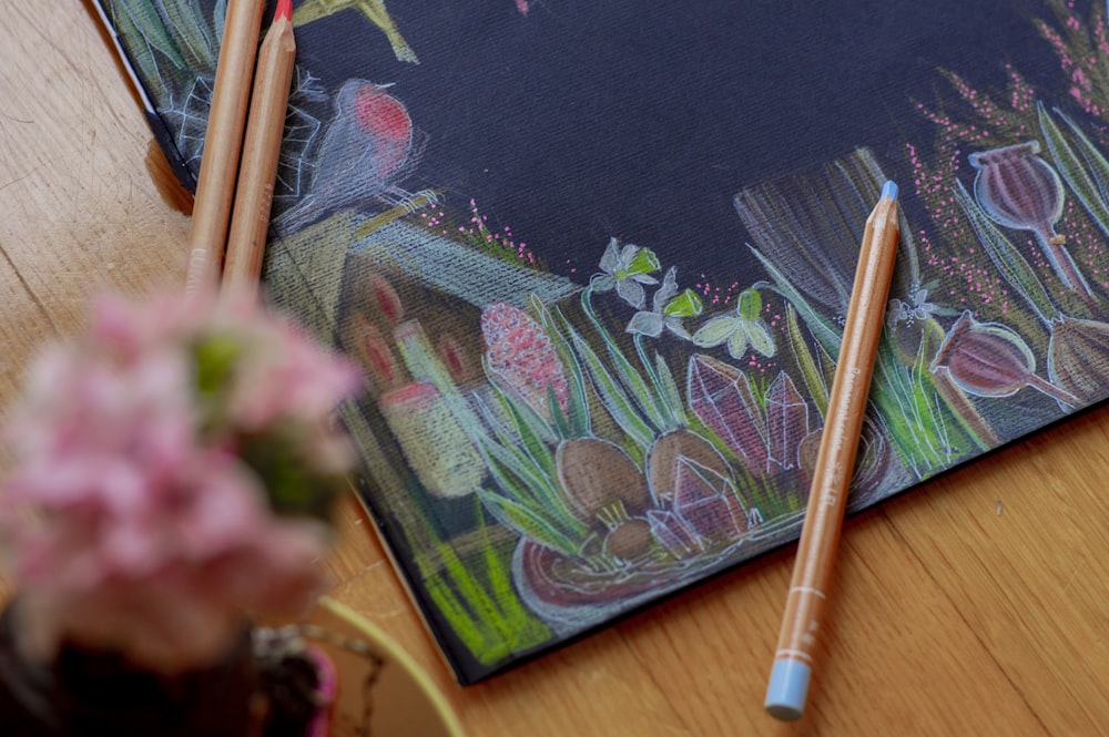 two pencils are laying on top of a drawing book