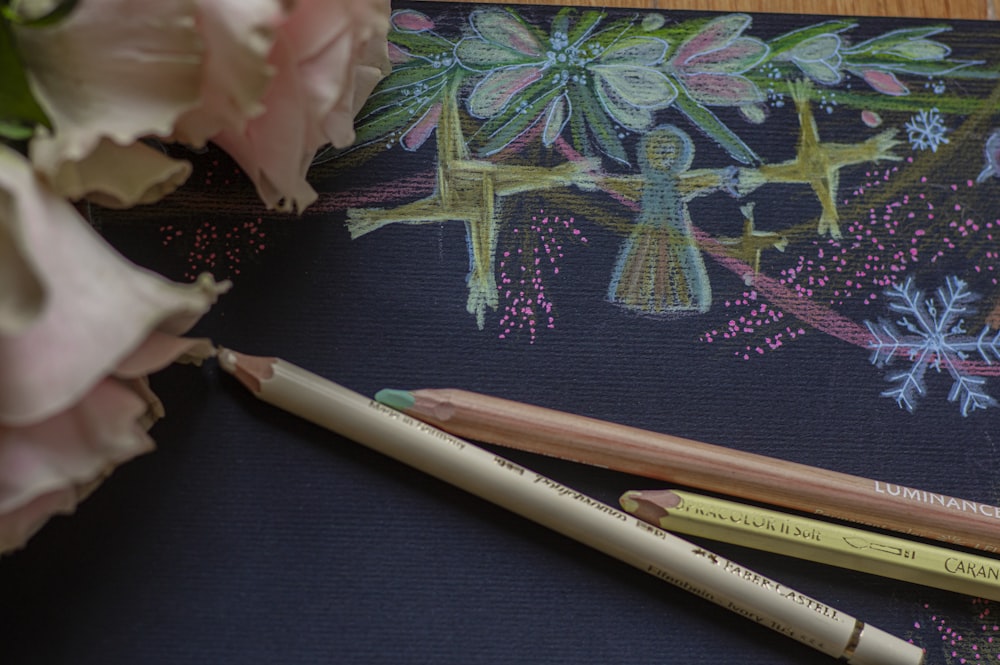 two pencils sitting on top of a table next to flowers