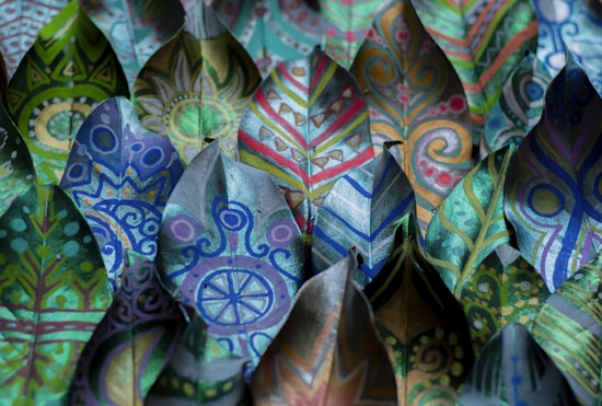 A collection of leaves beautifully painted with intricate patterns and vibrant colors, featuring geometric shapes, swirls, and abstract designs. Each leaf has its unique pattern, showcasing a range of artistic styles.