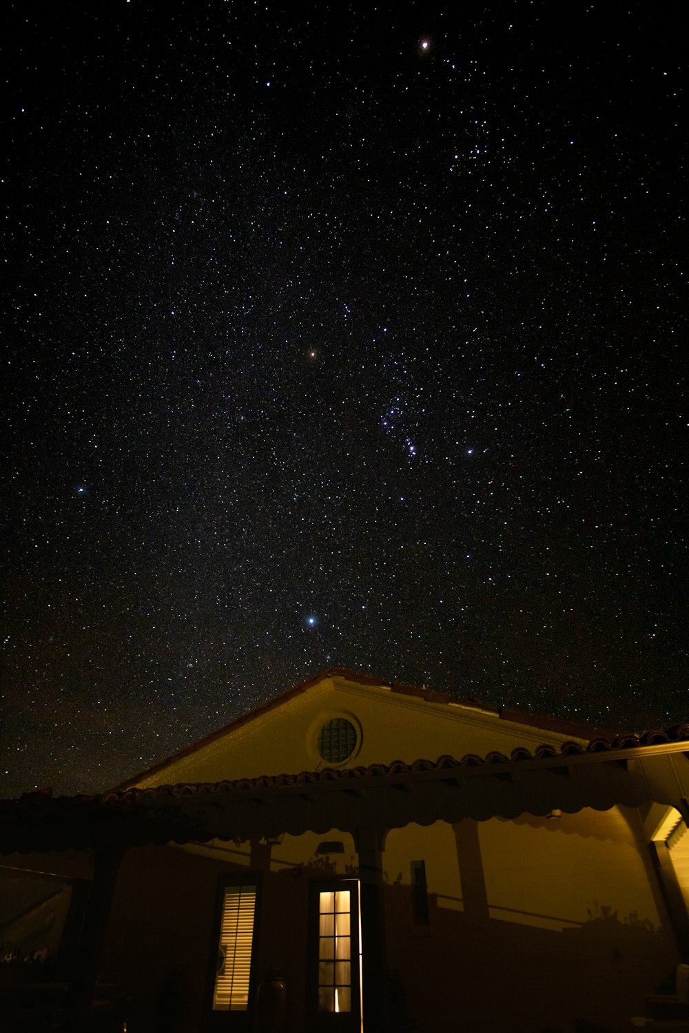 the night sky with stars above a house