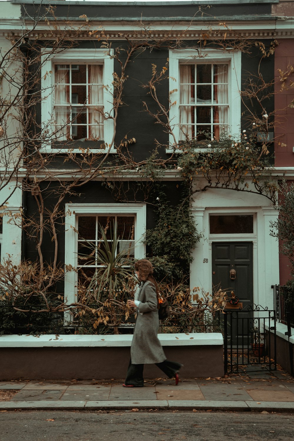 a woman walking down a street past a tall building