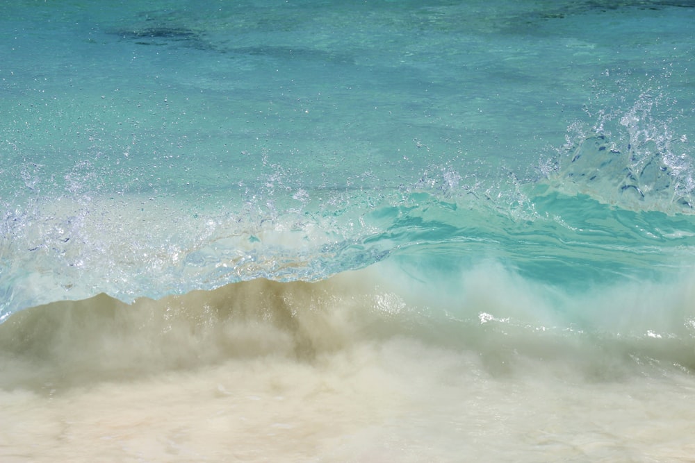 an ocean wave is breaking on a sandy beach