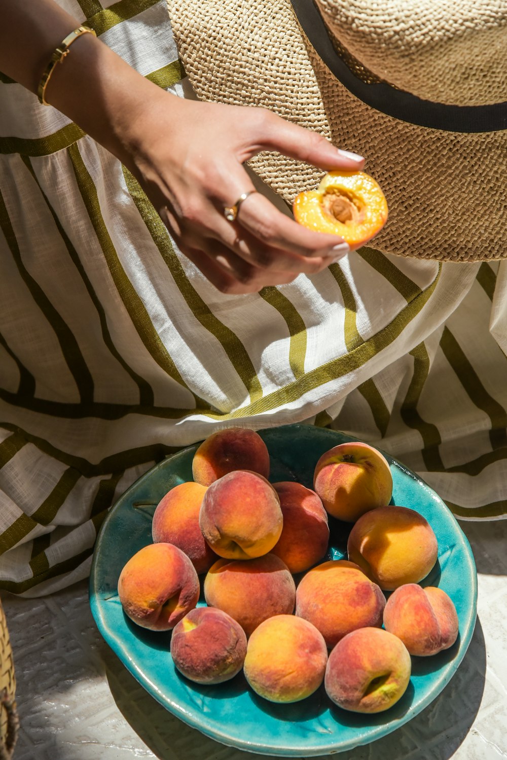 a woman holding a piece of fruit in front of a plate of peaches