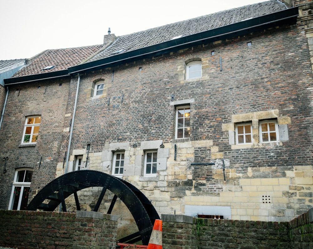 an old brick building with a water wheel in front of it