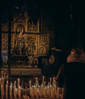 Candles flickering softly on an altar adorned with flowers and religious icons.