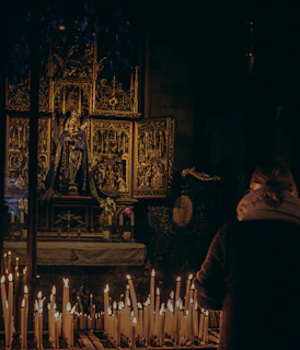A silhouette of a person praying in front of a candlelit altar