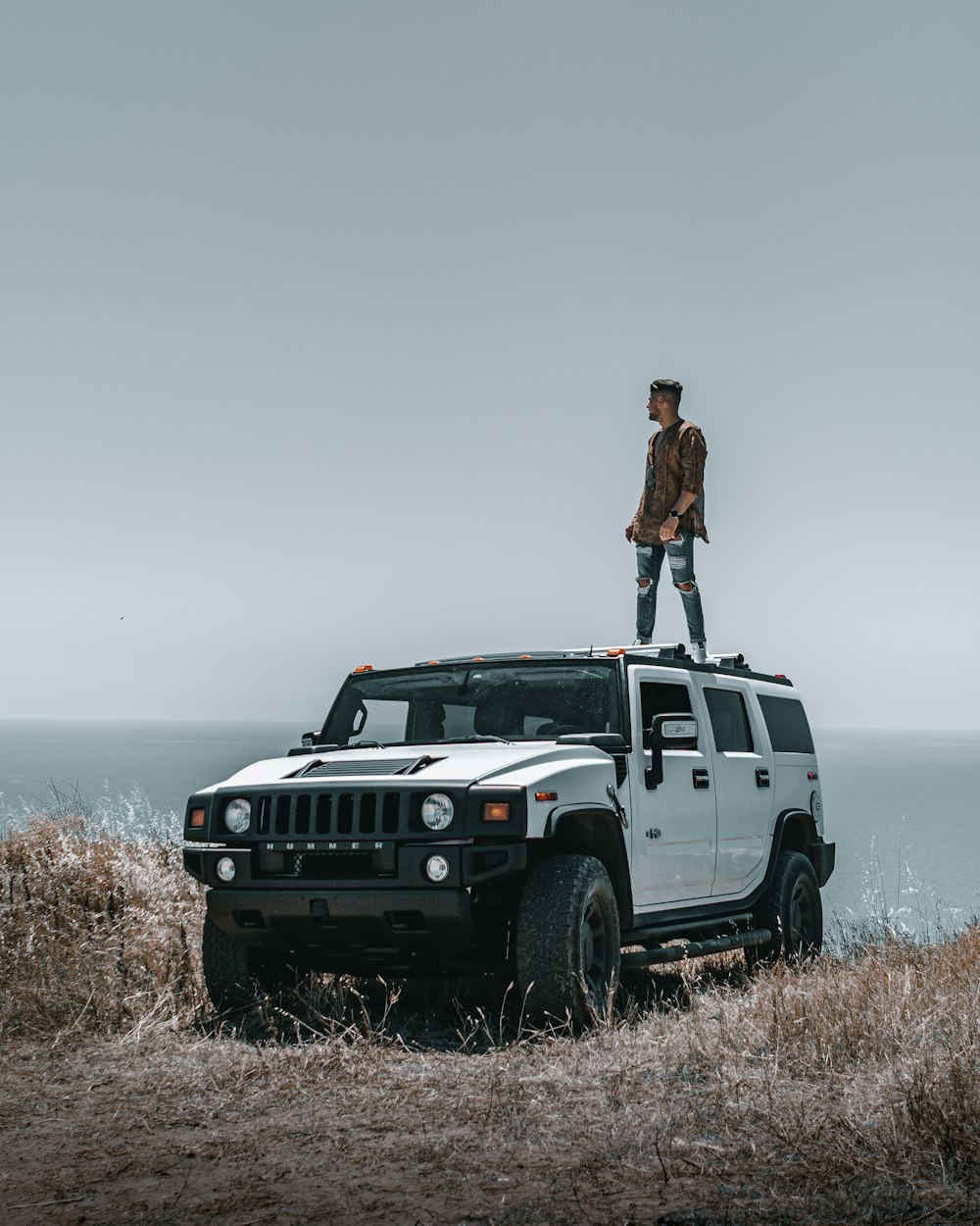 a man standing on top of a white hummer truck