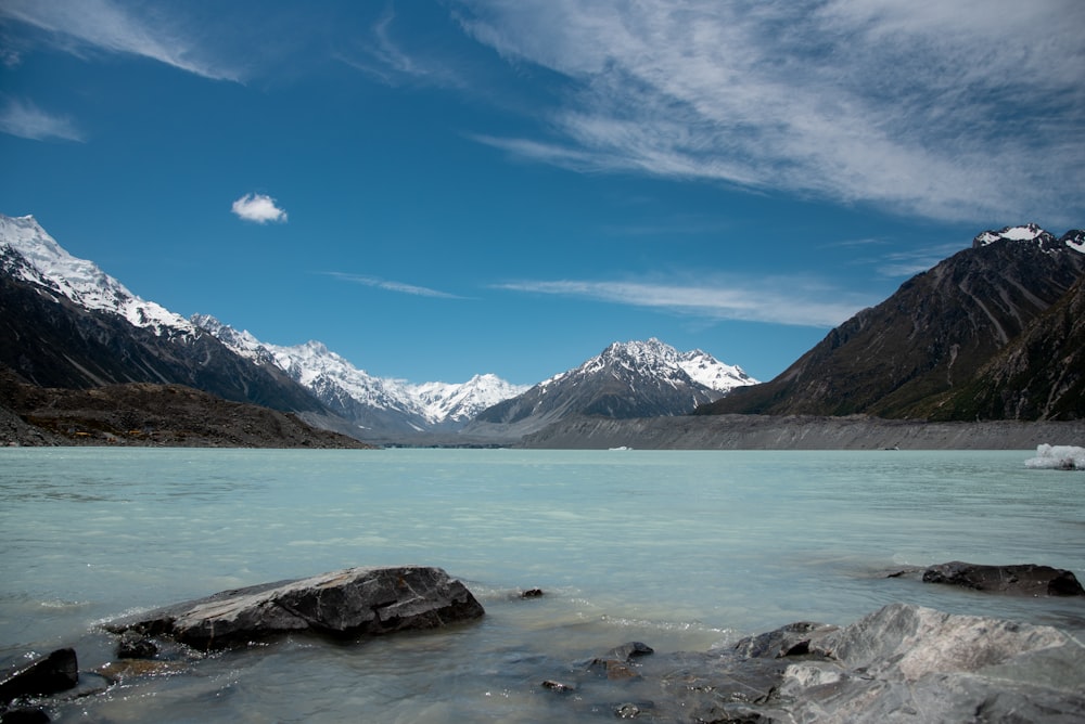a body of water surrounded by mountains under a blue sky