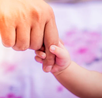 a close up of a person holding a baby's hand
