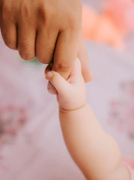a close up of a person holding a baby's hand