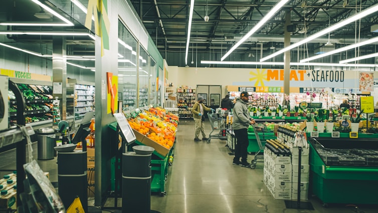 A bustling local supermarket aisle filled with fresh produce and smiling customers.