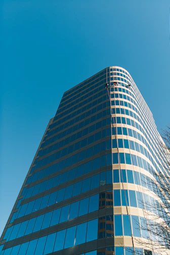 Close-up of skilled workers installing sleek glass panels on a modern building facade under a clear sky.