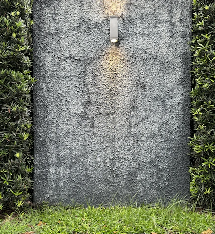 A sleek charcoal-colored retaining wall with integrated lighting highlighting the landscaping.