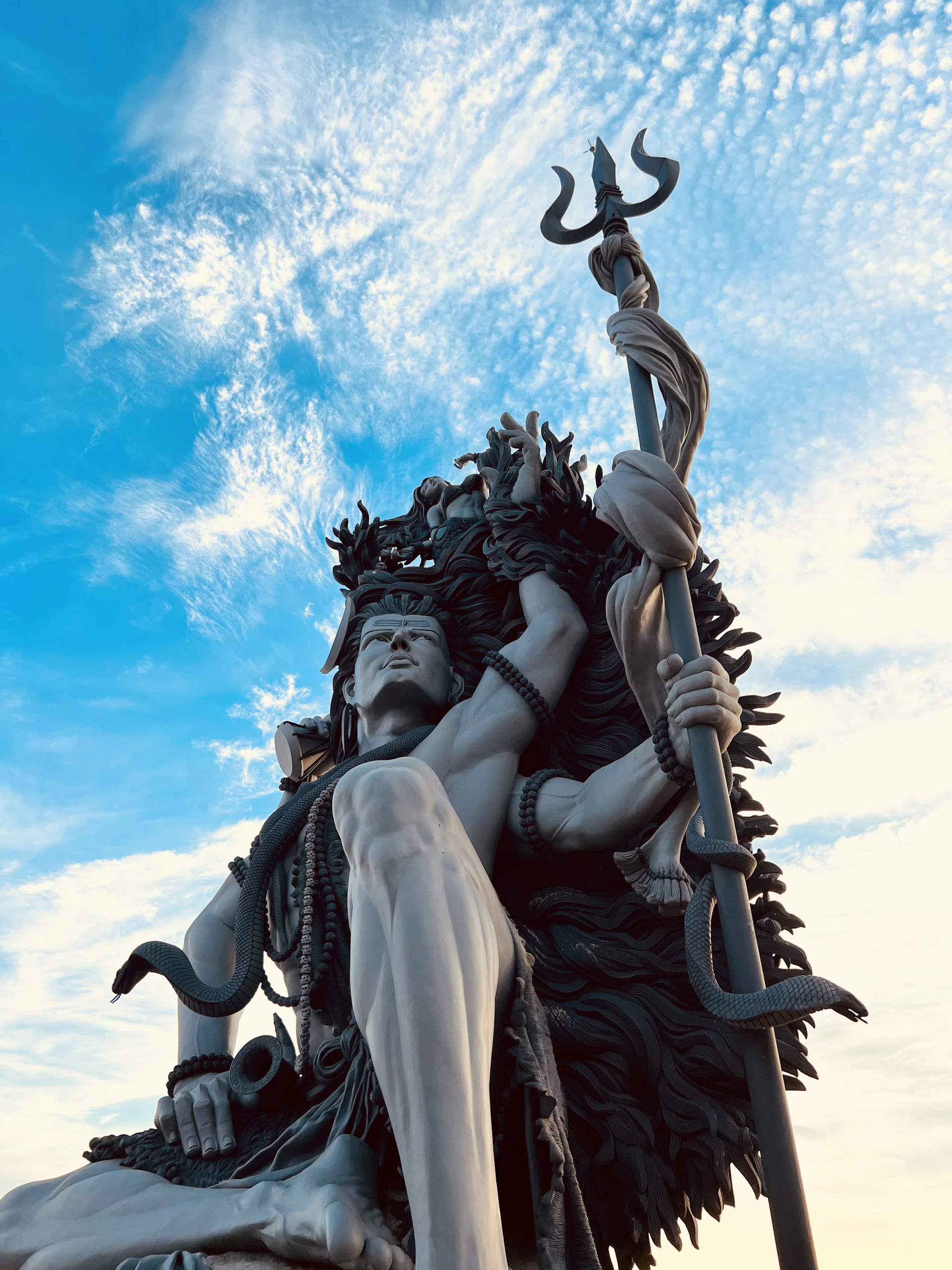a statue of a man holding a spear with a sky background