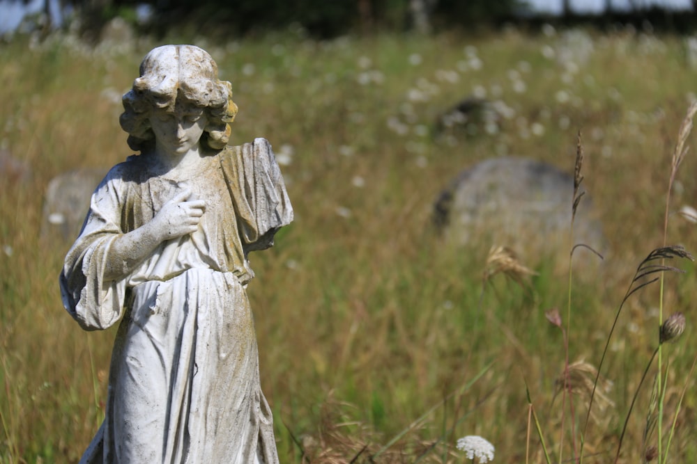 a statue of a woman holding a book in a field