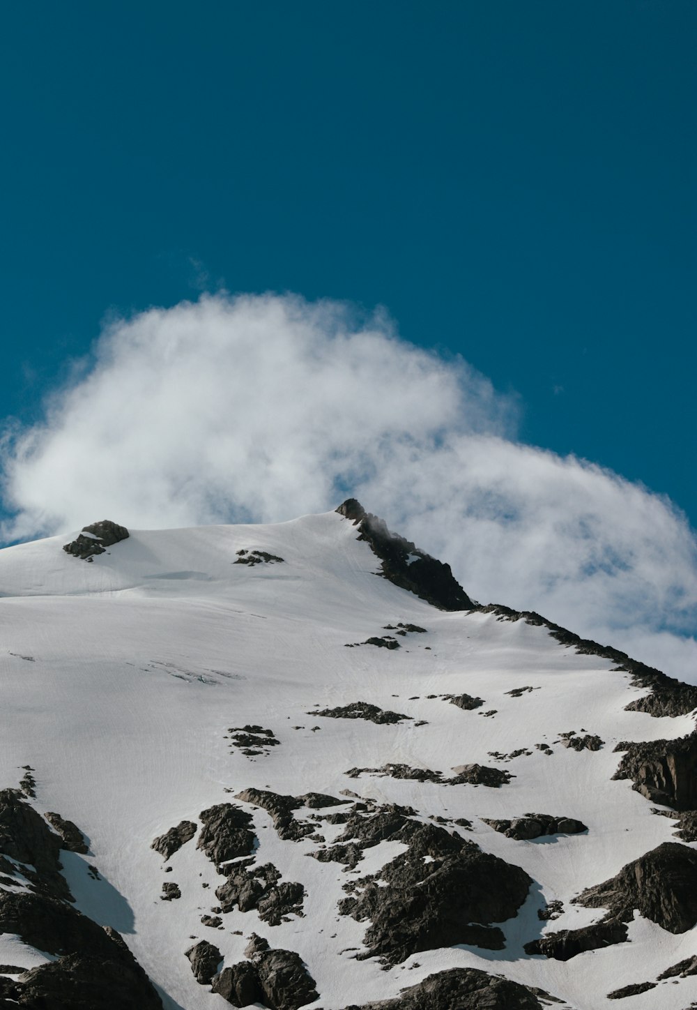 a snow covered mountain with a cloud in the sky