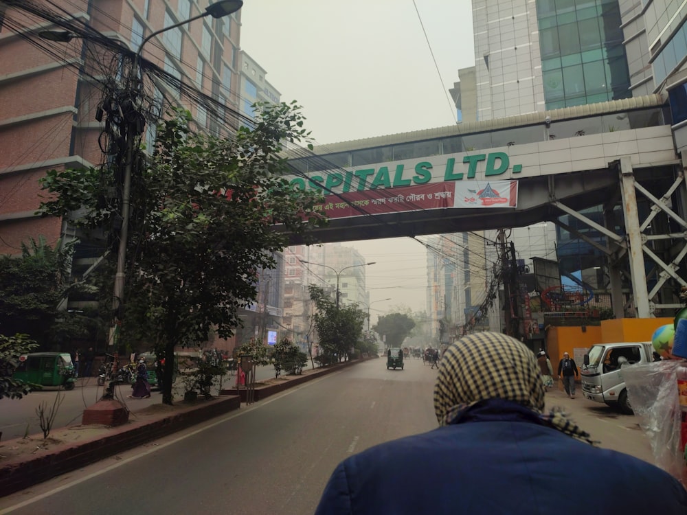 a man walking down a street under a bridge