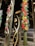 Decorative bamboo stalks with intricate patterns cut into them are displayed. They are illuminated from within, creating a warm glow. Some of the surrounding stalks are adorned with colorful flowers that feature red, yellow, and white blooms.