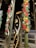 Decorative bamboo stalks with intricate patterns cut into them are displayed. They are illuminated from within, creating a warm glow. Some of the surrounding stalks are adorned with colorful flowers that feature red, yellow, and white blooms.