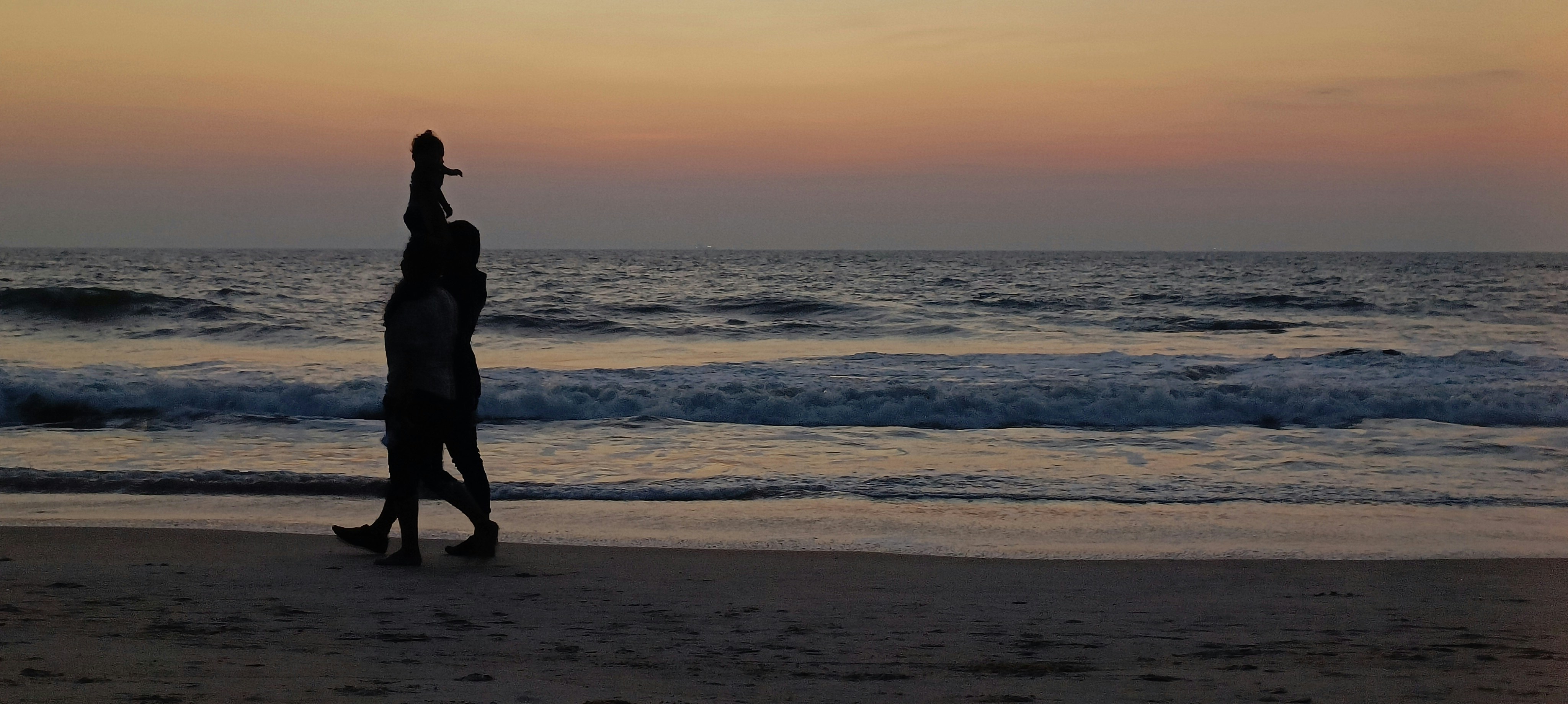 Person standing on a beach holding a surfboard