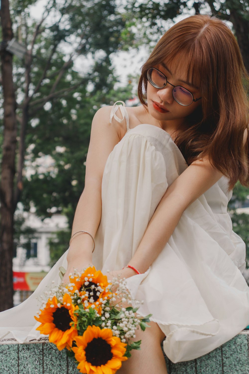 a woman in a white dress holding a bouquet of sunflowers