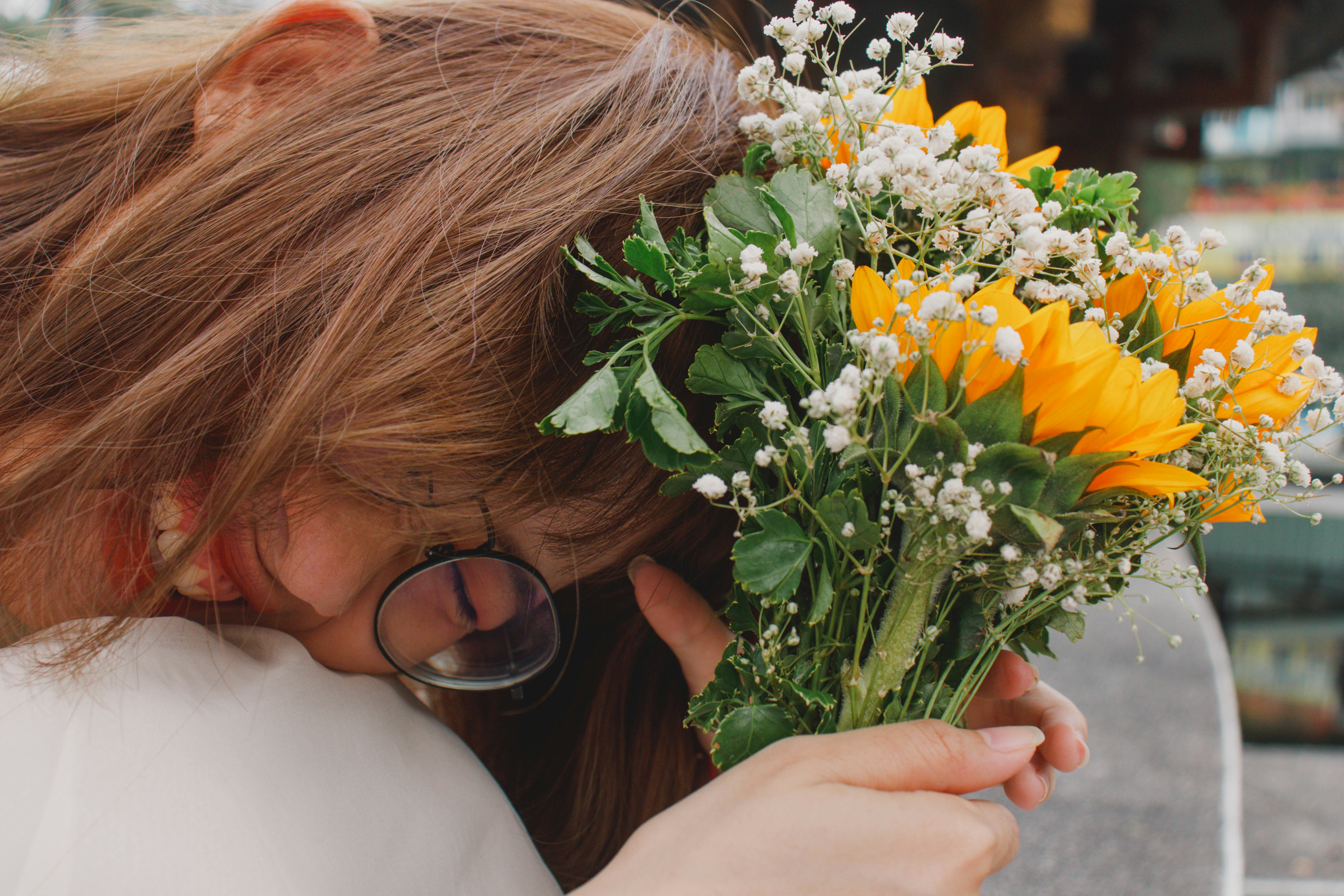 a woman holding a bouquet of sunflowers in her hand