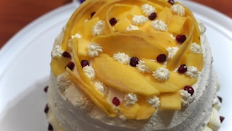 A vibrant mango mousse cake decorated with fresh mango slices and marigold petals.