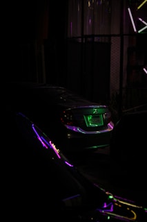 Nighttime shot of a car with neon underglow parked outside the hackerspace, reflecting the dark professional aesthetic