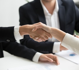 two people shaking hands in front of a laptop