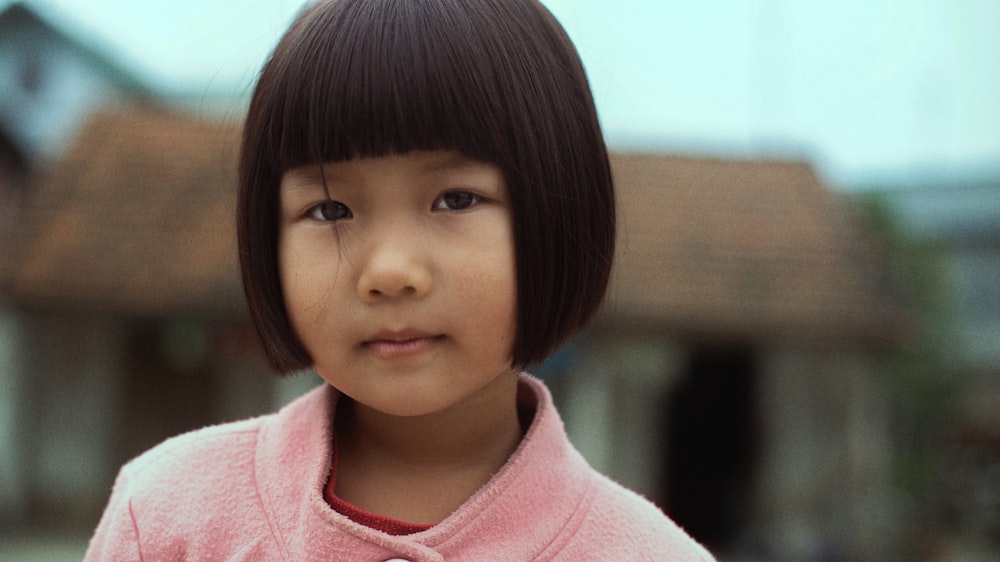 une petite fille avec une chemise rose et des cheveux noirs