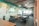 An open office workspace featuring several desks with ergonomic chairs. The walls are decorated with a nature-themed mural and the phrase 'Capture the Nature' is prominently displayed. Overhead, modern light fixtures and exposed ductwork add an industrial touch. Natural light filters in through large windows, enhancing the workspace.