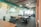 An open office workspace featuring several desks with ergonomic chairs. The walls are decorated with a nature-themed mural and the phrase 'Capture the Nature' is prominently displayed. Overhead, modern light fixtures and exposed ductwork add an industrial touch. Natural light filters in through large windows, enhancing the workspace.
