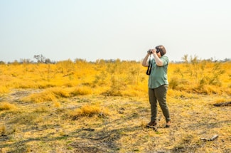 a man standing in a field taking a picture with a camera