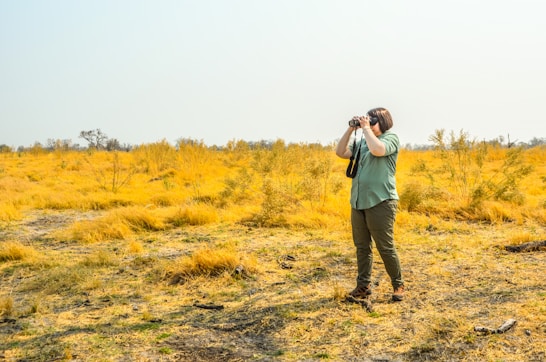 a man standing in a field taking a picture with a camera