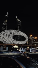 a picture of a city at night with cars parked in front of it