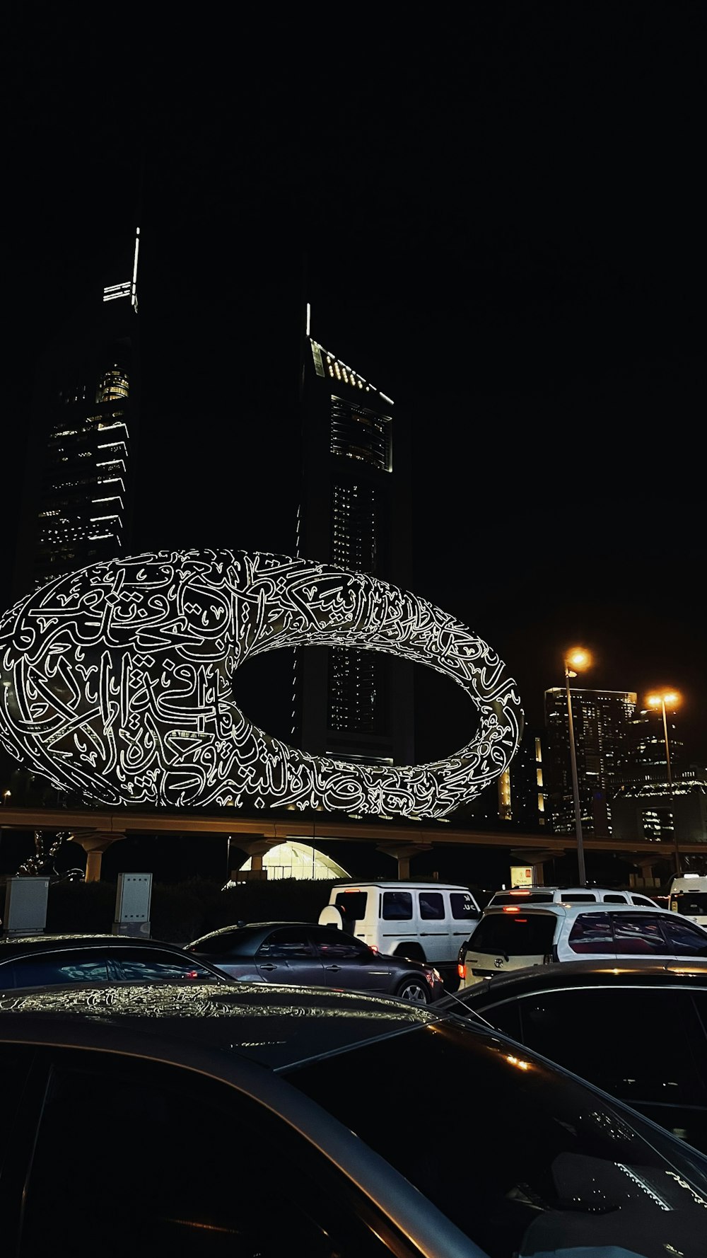 a picture of a city at night with cars parked in front of it