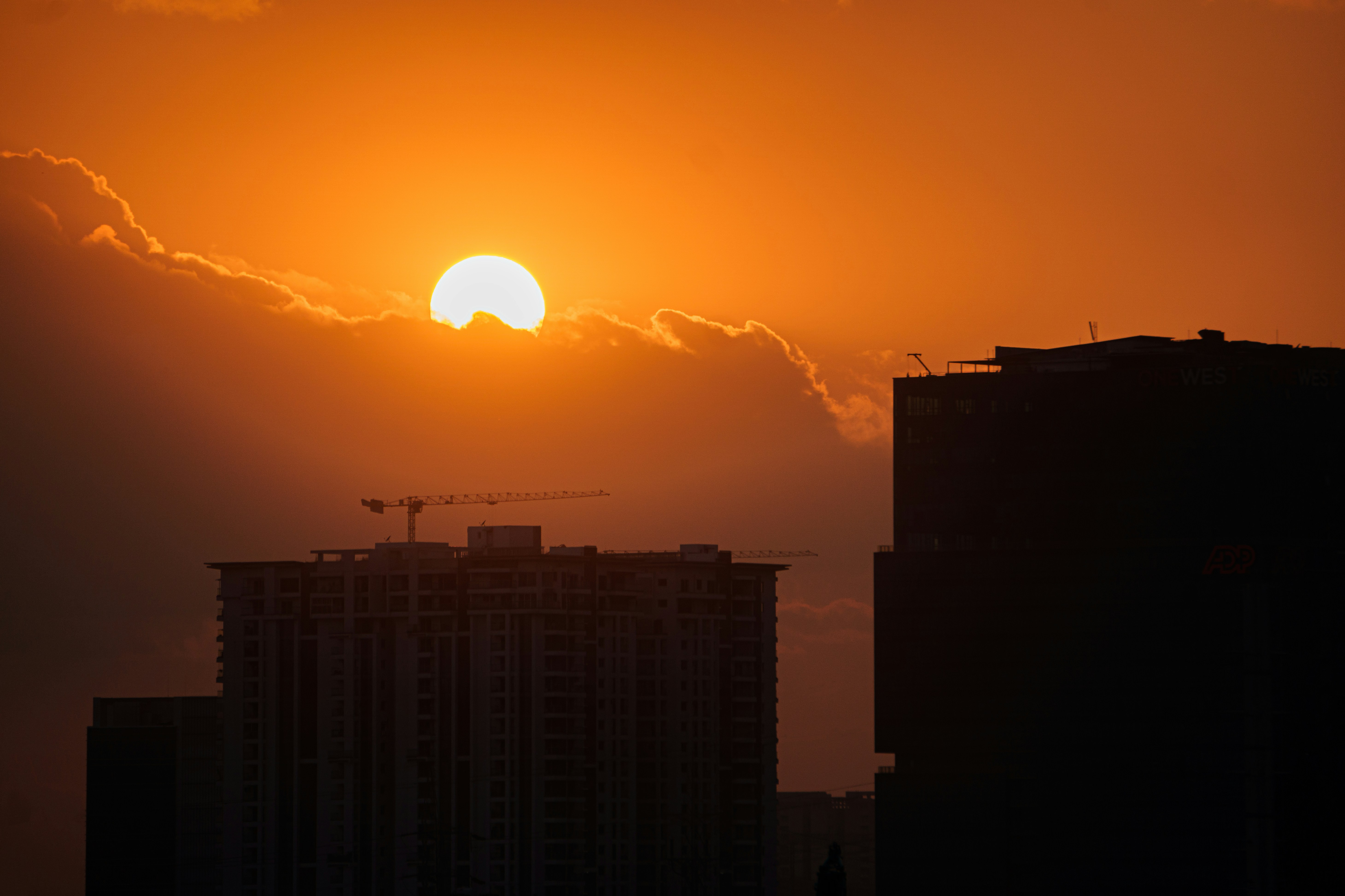 the sun is setting over a city with tall buildings