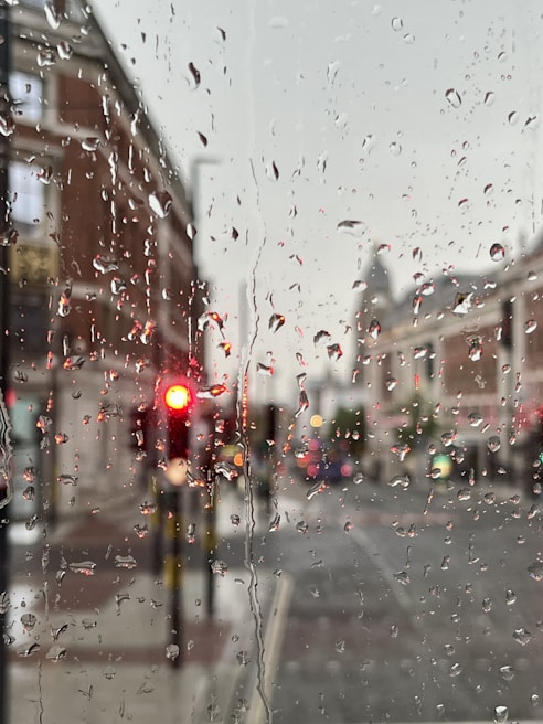 Raindrops glistening on a city street with blurred traffic lights in the background